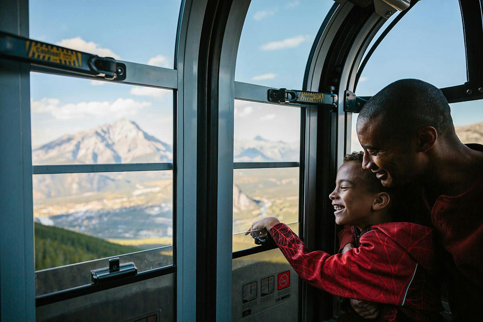 Leende far och son tittar ut från Banff Gondola